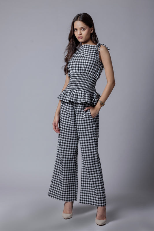 A model wearing a check-patterned co-ord set with a peplum top and straight-fit pants.