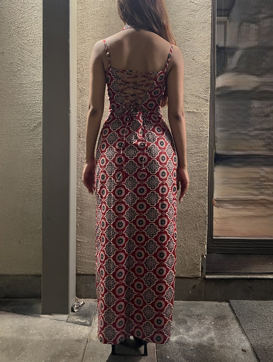 woman wearing a sleeveless red block printed cotton dress and black patterned maxi dress with a high slit, and a corset tie-up back & a neck band.
