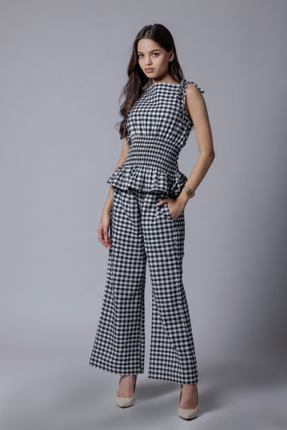 A model wearing a check-patterned co-ord set with a peplum top and straight-fit pants.
