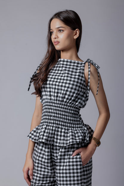 A model wearing a check-patterned co-ord set with a peplum top and straight-fit pants.