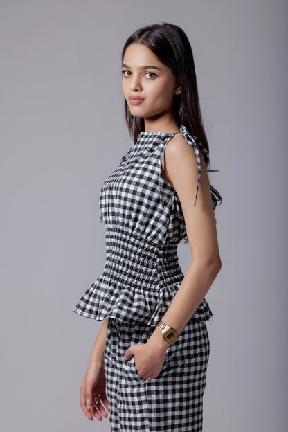A model wearing a check-patterned co-ord set with a peplum top and straight-fit pants.