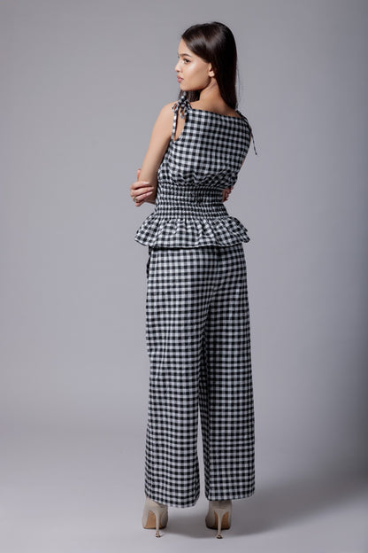A model wearing a check-patterned co-ord set with a peplum top and straight-fit pants.