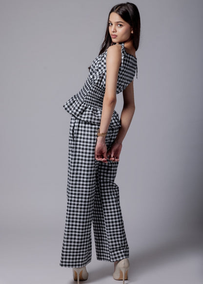 A model wearing a check-patterned co-ord set with a peplum top and straight-fit pants.