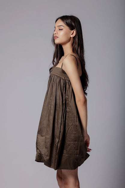 A model wearing a mocha brown, puffier silhouette dress with adjustable straps and a flared design.