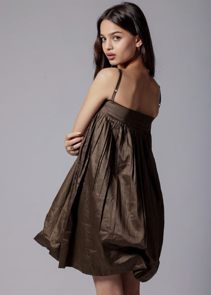 A model wearing a mocha brown, puffier silhouette dress with adjustable straps and a flared design.