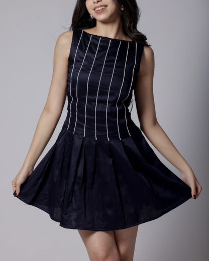 Model in a navy blue sleeveless dress with white piping, flared bottom, and adjustable back bow from Hyghbreed