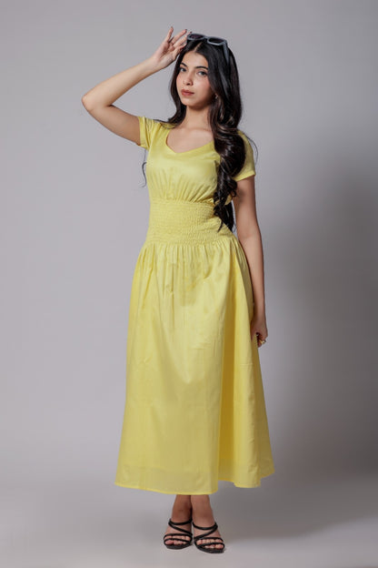A woman wearing a lemon-yellow cotton long dress with a ruched waist, V-round neckline, and short sleeves.