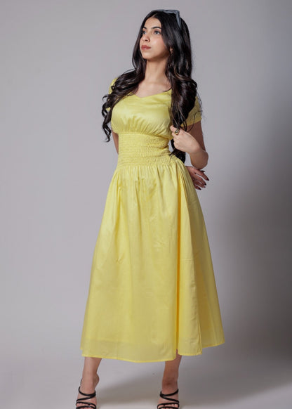 A woman wearing a lemon-yellow cotton long dress with a ruched waist, V-round neckline, and short sleeves.