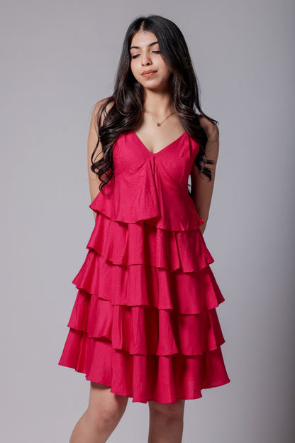 A woman in a bright pink, sleeveless, V-neck, flared mini dress with adjustable straps and an all-over flare design.