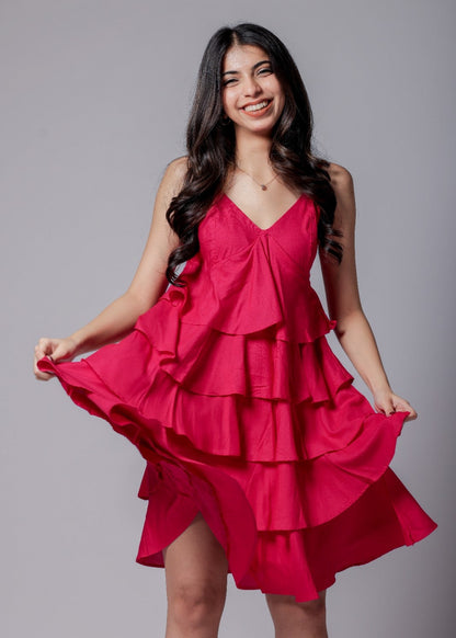 A woman in a bright pink, sleeveless, V-neck, flared mini dress with adjustable straps and an all-over flare design.