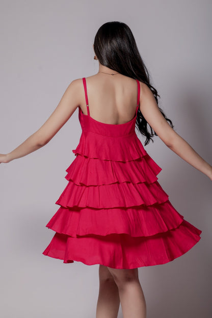 A woman in a bright pink, sleeveless, V-neck, flared mini dress with adjustable straps and an all-over flare design.