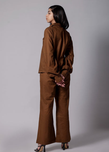 A female wearing a pure cotton brown co-ord set with a gathered tailored shirt and flowy pants.