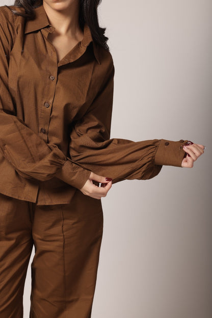 A female wearing a pure cotton brown co-ord set with a gathered tailored shirt and flowy pants.
