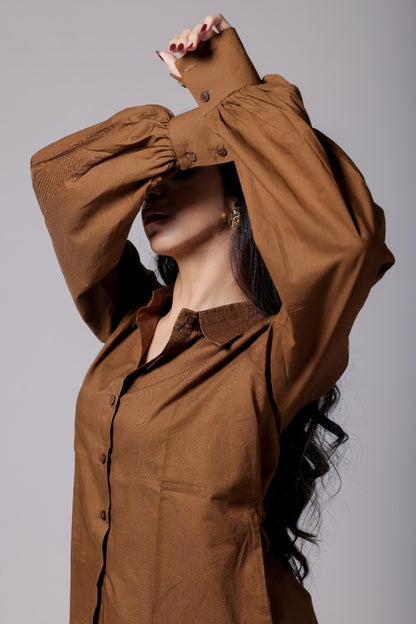 A female wearing a pure cotton brown co-ord set with a gathered tailored shirt and flowy pants.