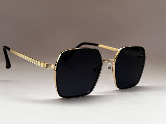 Sunglasses with gold frame and black lenses on a gray background