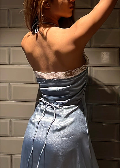 A woman wearing a blue satin halter dress with lace trim, and intricate lace detailing's with side zipper and back tie-up that snatches the waist