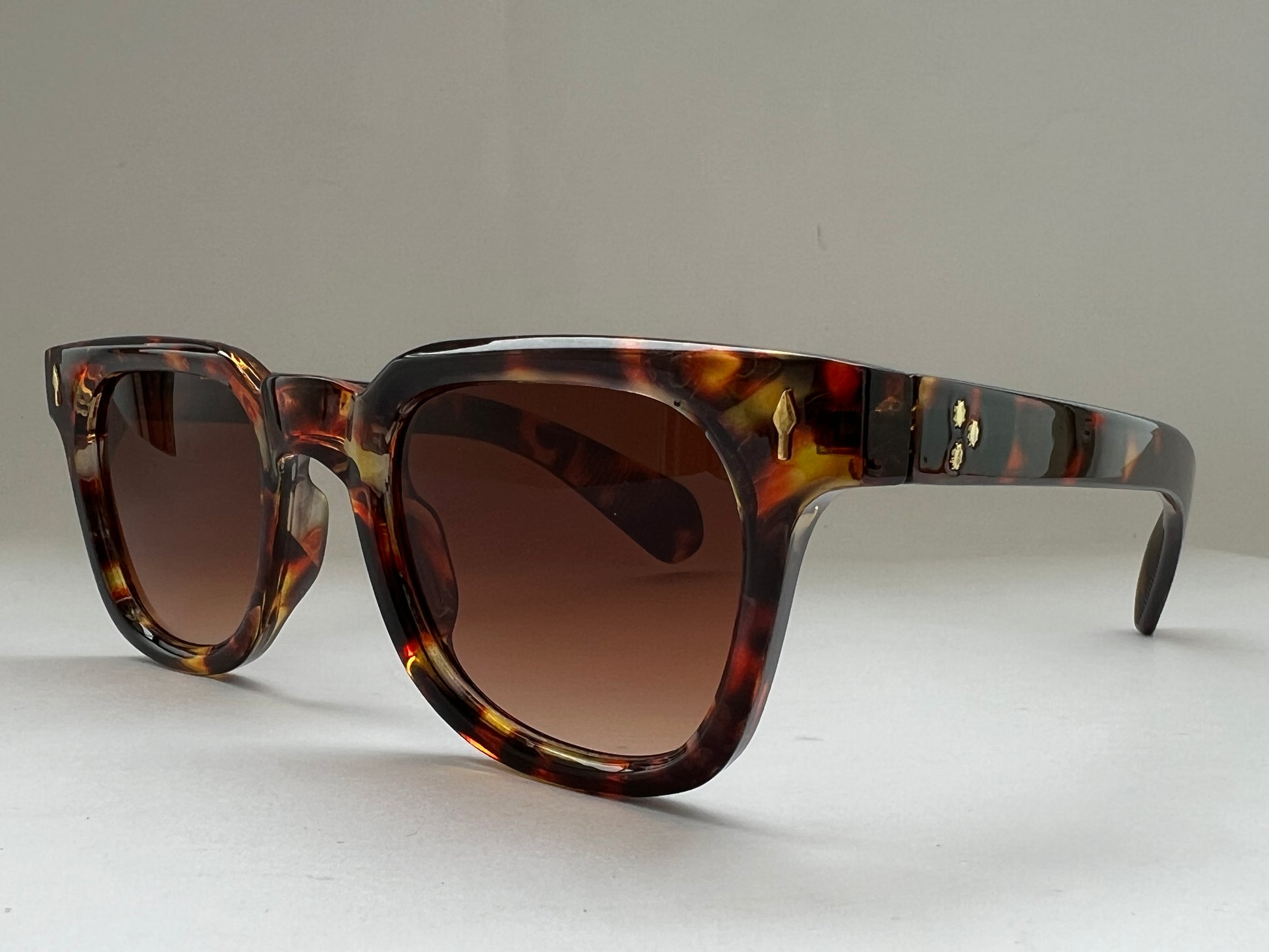 Sunglasses with tortoiseshell frame and brown lenses on a light gray background