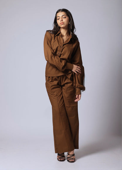 A female wearing a pure cotton brown co-ord set with a gathered tailored shirt and flowy pants.