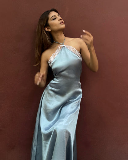 A woman wearing a blue satin halter dress with lace trim, and intricate lace detailing's with side zipper and back tie-up that snatches the waist