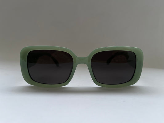 Green sunglasses with dark lenses on a light gray background