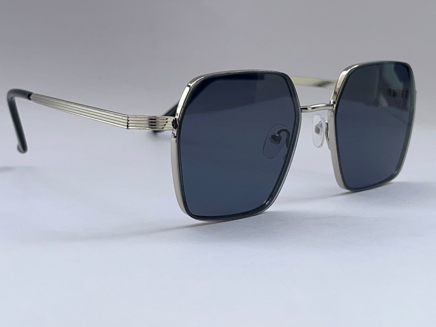 Sunglasses with dark lenses and gold frame on a light gray background