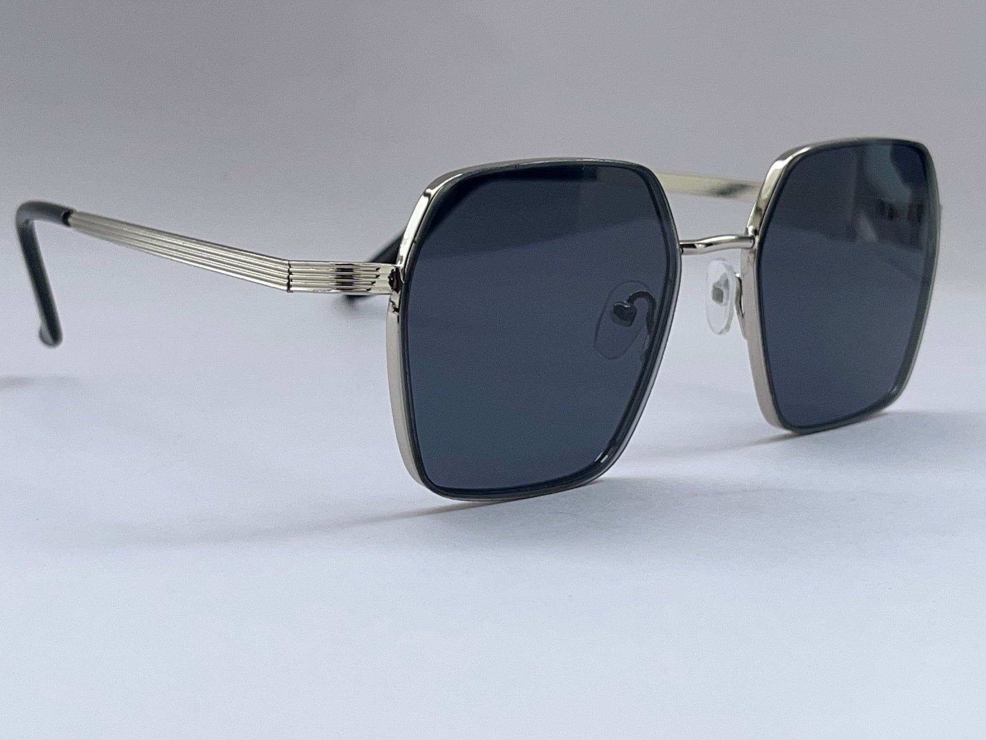 Sunglasses with dark lenses and gold frame on a light gray background
